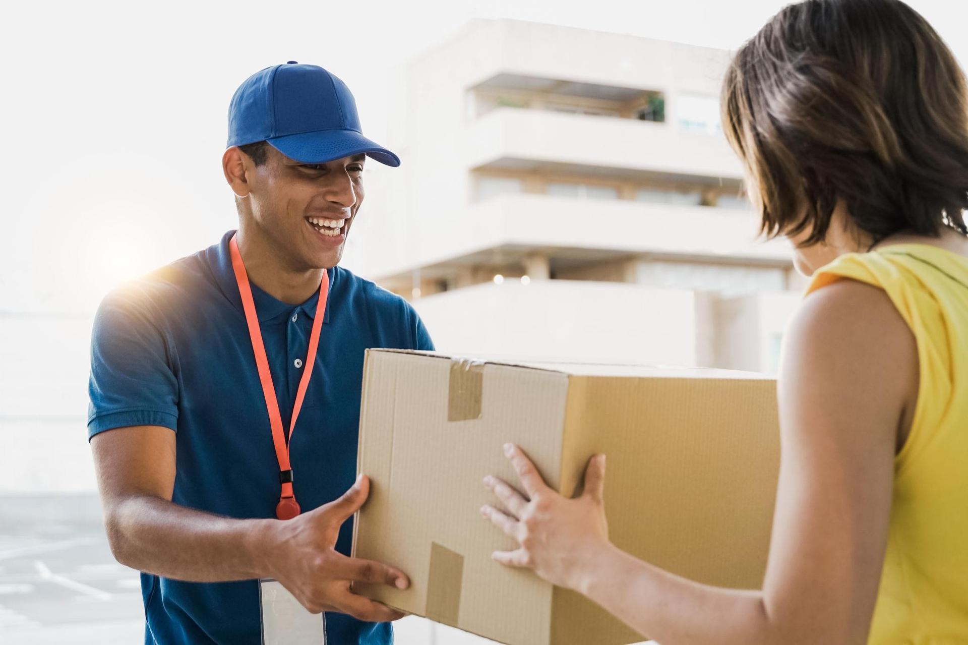 Smiling courier handing a cardboard parcel to a customer