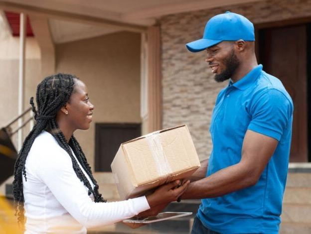 Courier in a blue uniform handing a parcel to a customer at her door