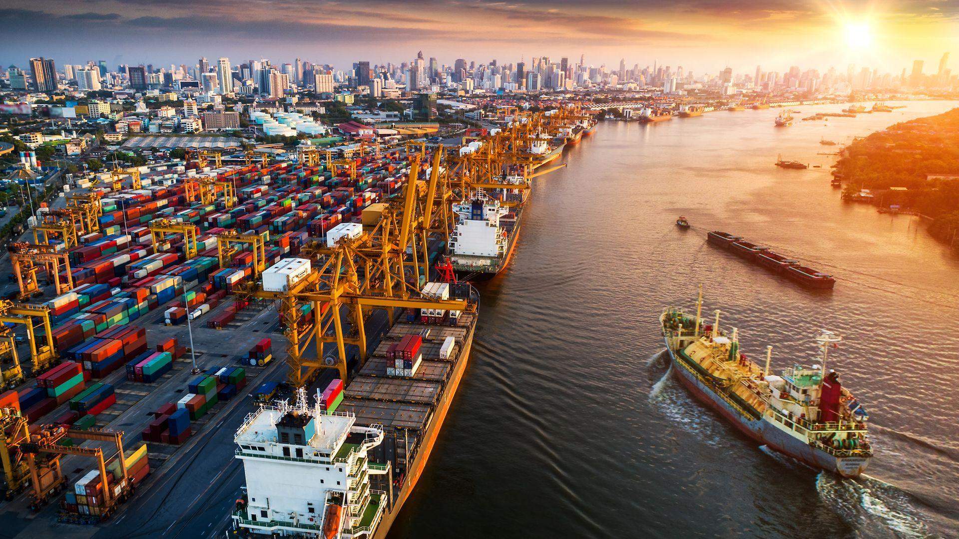 Container port and city skyline at sunset
